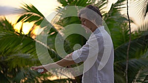 Superslowmotion shot of a young man applying an antimosquito repellent spray on his skin. A tropical background