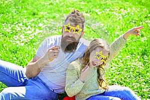 Superstar concept. Family spend leisure outdoors. Father and daughter sits on grass at grassplot, green background