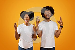 Superstitious african american couple cross fingers on yellow