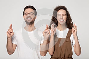 Superstitious happy guy and girl standing with crossed fingers.