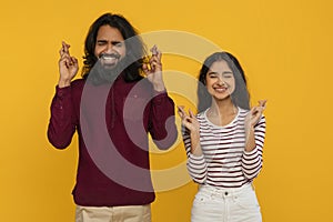 Superstitious young indian man and woman cross fingers