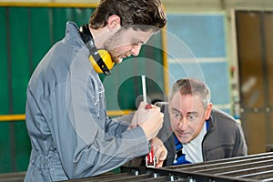 Supervisor checking work apprentice engineer in factory