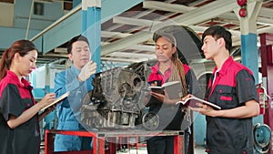 Supervisor engineer is teaching mechanic workers about car engines at a garage.