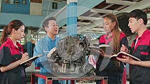 Supervisor engineer is teaching mechanic workers about car engines at a garage.