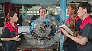 Supervisor engineer is teaching mechanic workers about car engines at a garage.