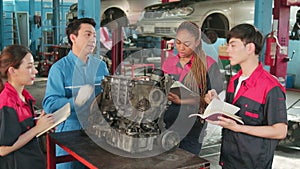 Supervisor engineer is teaching mechanic workers about car engines at a garage.