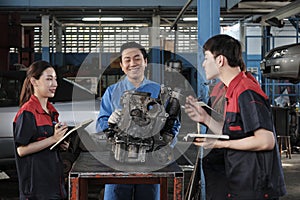 Supervisor engineer is teaching mechanic workers about car engines at a garage.