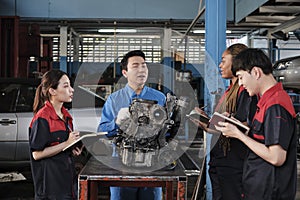 Supervisor engineer is teaching mechanic workers about car engines at a garage.