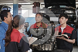 Supervisor engineer is teaching mechanic workers about car engines at a garage.