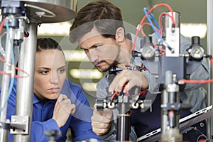 supervisor explaining factory machinery to female trainee