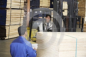 Supervisor By Laborer With Forklift Carrying Wood