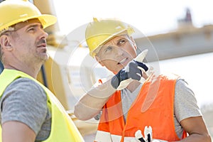 Supervisor showing something to colleague at construction site on sunny day