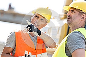 Supervisor showing something to colleague at construction site on sunny day