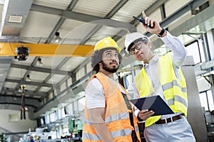 Supervisor showing something to manual worker in metal industry