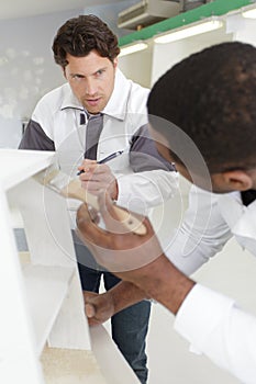 supervisor watching apprentice painter use roller