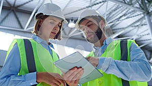 Supervisors checking tablet discussing manufacturing information analysing