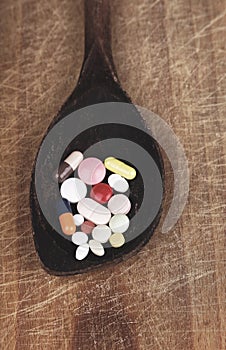 Suplements pills on wooden spoon