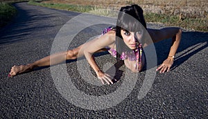 Supple woman crouches on a country road.