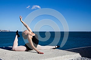 Supple young dancer does the splits on a big stone block.