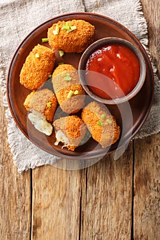 Suppli al telefono italian fast food fried tomato rice croquettes stuffed with mozzarella closeup on the plate. Vertical top view