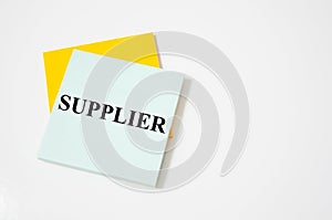 Suppliers - blue binder in the office. supplier text written on a white notepad with colored pencils and a yellow background