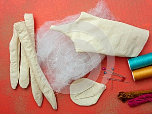 Supplies for sewing a rag doll on a red background