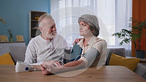 support and care, elderly couple using blood pressure monitor to the wife with hypertension in the house