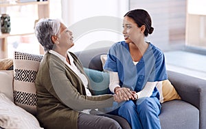 Support, caregiver holding hands with a senior woman and on sofa at nursing home for care. Consulting or healthcare