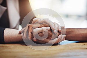 Support, compassion and trust while holding hands and sitting together at a table. Closeup of a loving, caring and