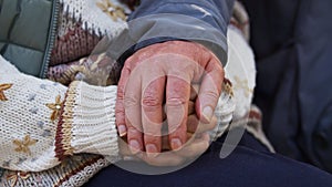 Support in illness concept. Wrinkled hands of two caucasian elderly senior people touching each other.