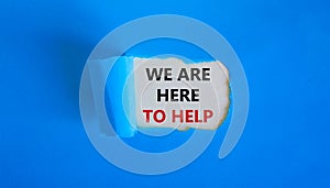 Support symbol. Words `we are here to help` appearing behind torn blue paper. Beautiful blue background. Business and support