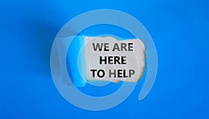 Support symbol. Words `we are here to help` appearing behind torn blue paper. Beautiful blue background. Business and support