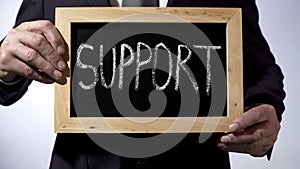 Support written on blackboard, businessman holding sign, business concept