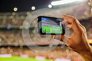 Supporter football team recording goal with mobile phone camera.