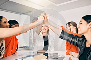 Supporting each other all the way to the top. a group of businesswoman giving each other a high five in an office at