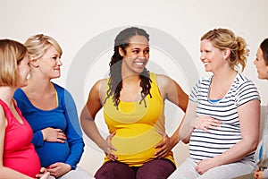 Supporting each other throughout their pregnancies. A multi-ethnic group of pregnant women smiling while sitting