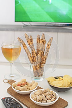 Supporting national team concept Football fan food Beer, peanuts, pistacios, potato chips and tv remote control