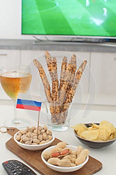 Supporting national team concept Football fan food Beer, peanuts, pistacios, potato chips and tv remote control