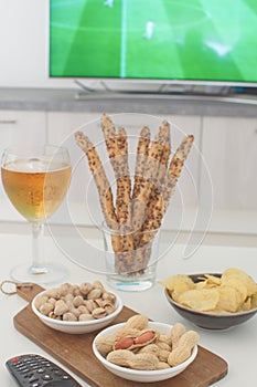 Supporting national team concept Football fan food Beer, peanuts, pistacios, potato chips and tv remote control