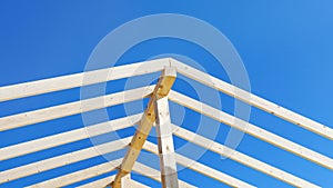 Supporting wooden structure for roof rafters, repeating beams on background of blue sky