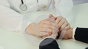 Supportive doctor holding patient's hands, telling bad news, sign of compassion