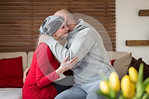 Supportive husband kissing his wife, cancer patient, after treatment in hospital. Cancer and family support.