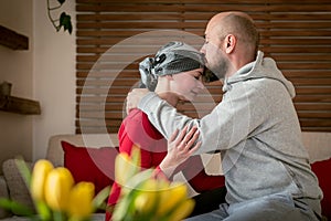 Supportive husband kissing his wife, cancer patient, after treatment in hospital. Cancer and family support.