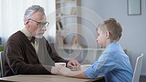 Supportive kid stroking grandpas hand, family going through hard times together