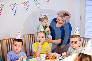 Supportive mother helping little boy to blow party horn