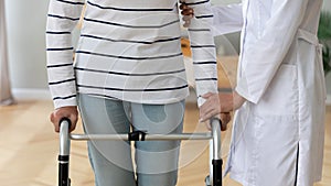 Supportive nurse help disabled old lady with walker
