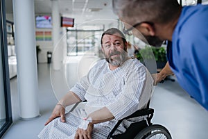 Supportive nurse soothing a worried patient in wheelchair. Illnesses and diseases in middle-aged men's health
