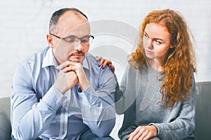 Supportive wife comforting her upset husband at meeting in counselor's office