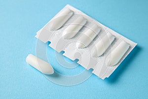 Suppository for anal or vaginal use on a blue background. Candles for treatment of hemorrhoids, temperature, thrush photo