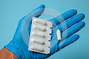 Suppository for anal or vaginal use in the hands of doctor in gloves. Candles for treatment of hemorrhoids, temperature photo
